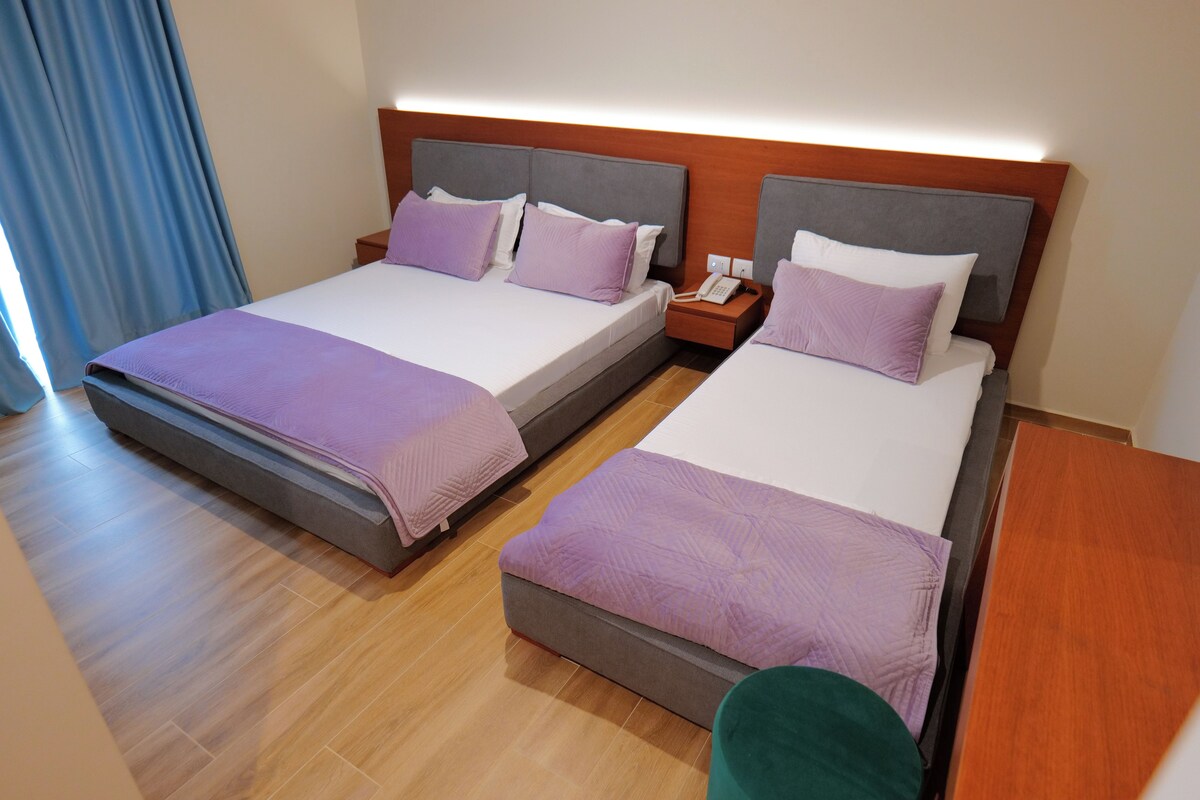 A hotel room with two beds, each with a headboard, bedside tables, and a telephone.