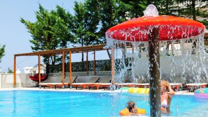 Piscina amb una font d'aigua, gandules i una zona d'estar coberta.