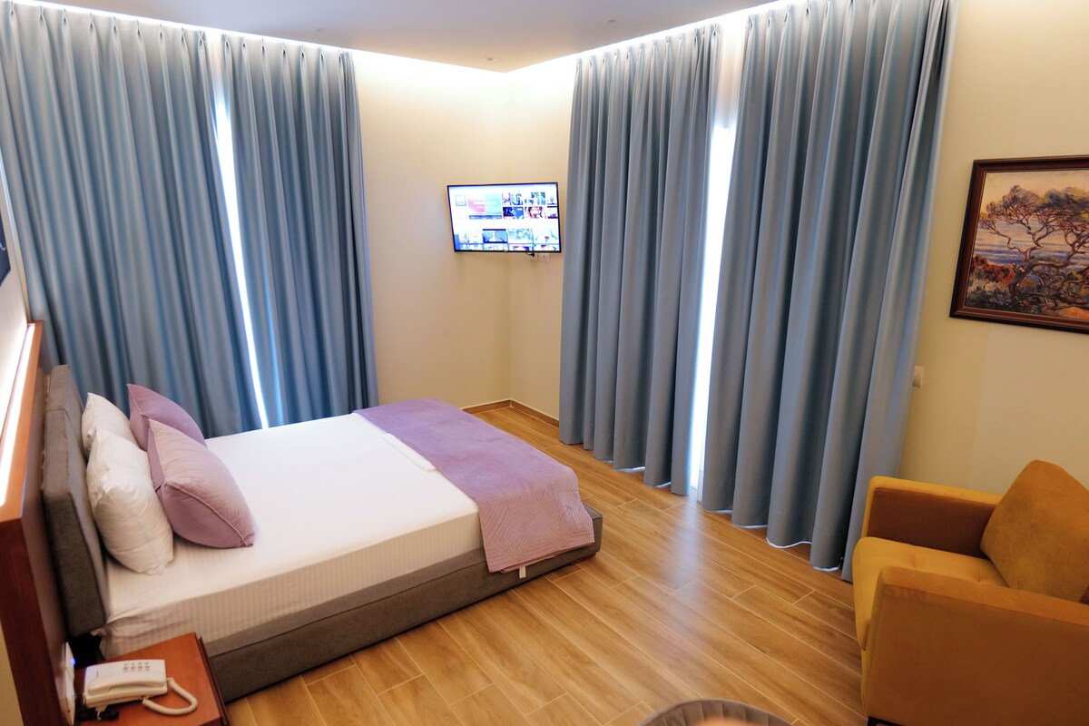 A hotel room with a bed, a television, a chair, and curtains.