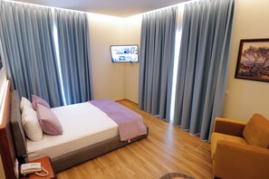 A hotel room with a bed, a television, a chair, and curtains.