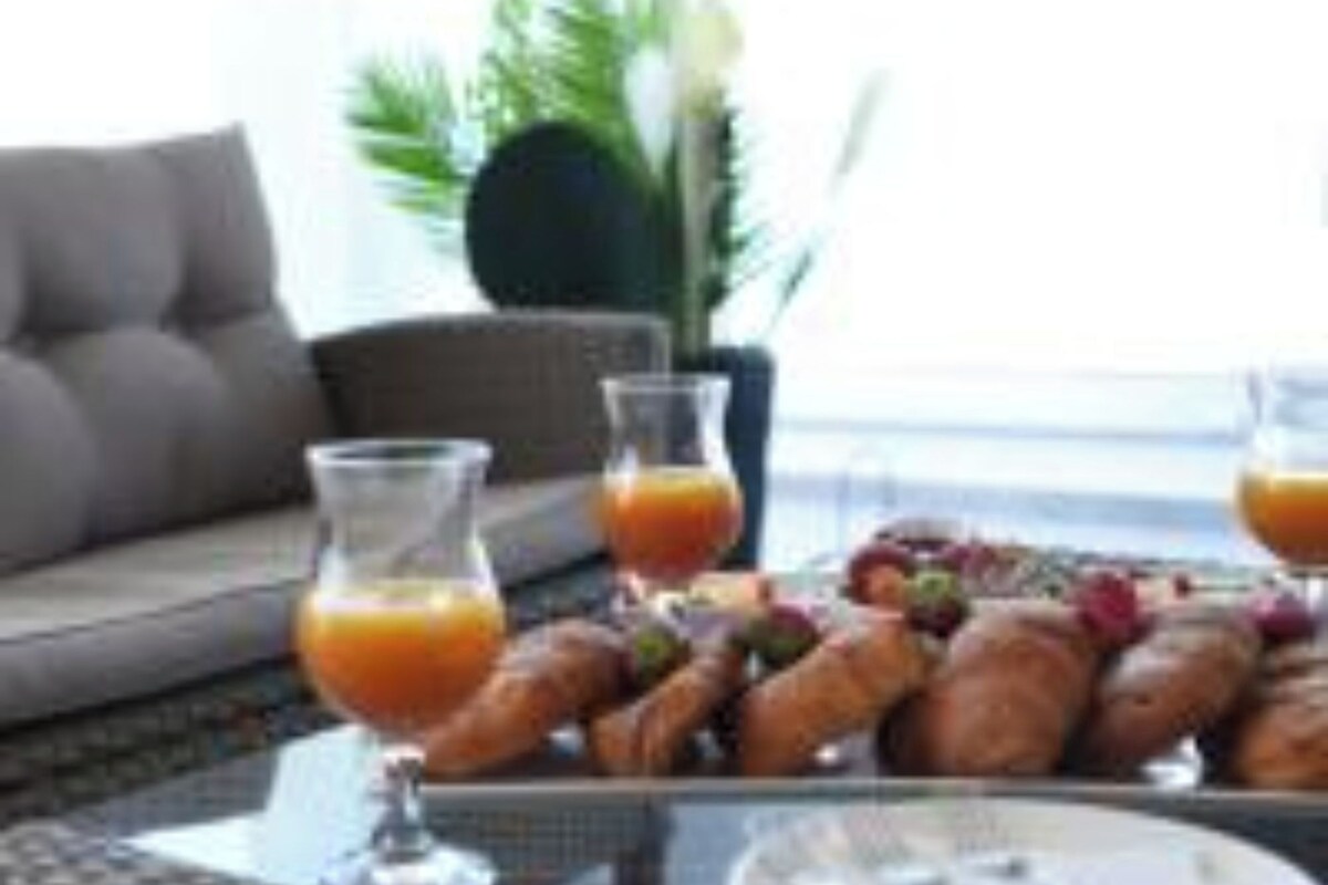 A breakfast setting with croissants, orange juice, and a plate on a table.