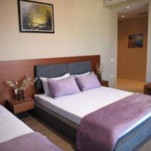 A hotel room with a large bed, a nightstand, a vase with flowers, and a painting on the wall. - 6 Miles Hotel (Ksamil)