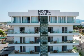 A multi-story hotel with balconies, large windows, and a central decorative column. - 6 Miles Hotel (Ksamil)
