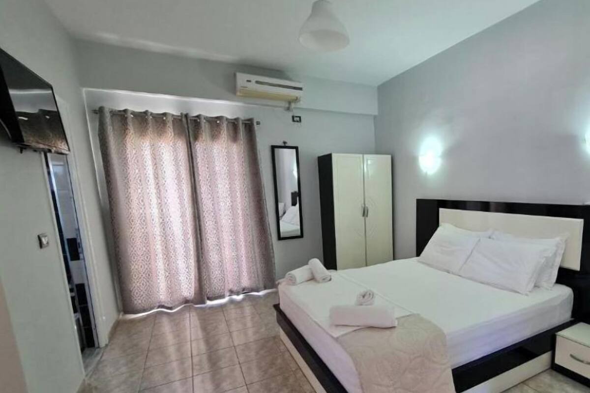 A bedroom with a bed, a wardrobe, a mirror, and an air conditioning unit.