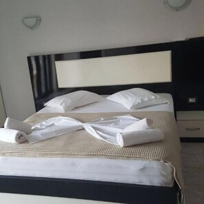 A neatly made bed with white linens, a black headboard, and a bedside table with a lamp.