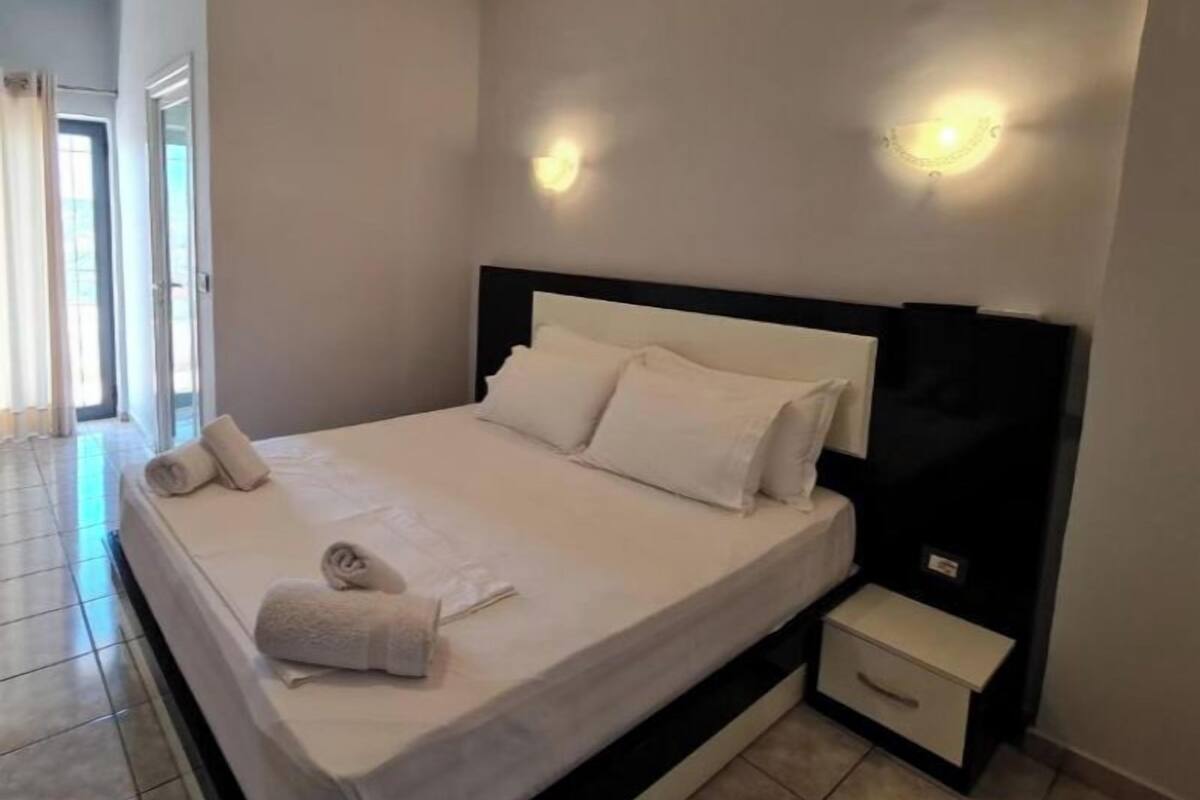 A bedroom with a bed, bedside tables, and a window.
