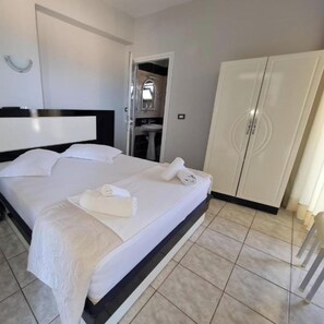 Une chambre d’hôtel avec un grand lit, une armoire et une salle de bain visible à travers une porte ouverte.