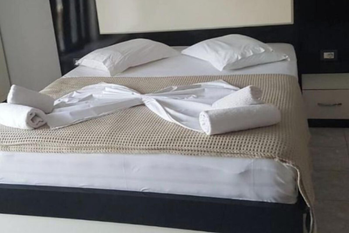 A neatly made bed with white linens, a black headboard, and a bedside table with a lamp.
