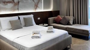 Une chambre d’hôtel moderne avec un grand lit, un canapé et un mur en marbre.