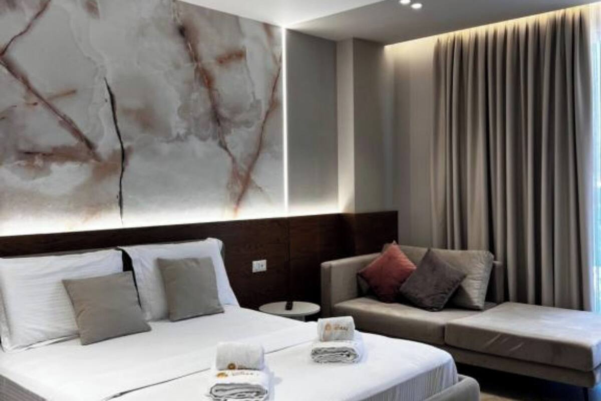 A modern hotel room with a large bed, a sofa, and a marble wall.