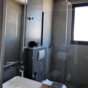 A modern bathroom with a glass shower enclosure, a white sink, and a marble wall. - Hotel Memmaj (Ksamil)