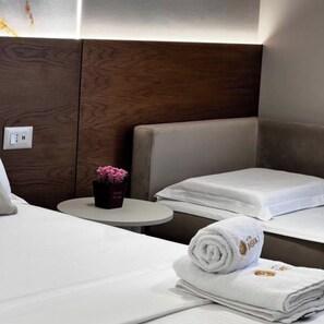 A hotel room with a bed, a small table with a potted plant, and a neatly folded towel. - Hotel Memmaj (Ksamil)