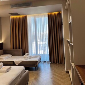 A hotel room with two beds, a wardrobe, and a large window with curtains. - Hotel Memmaj (Ksamil)
