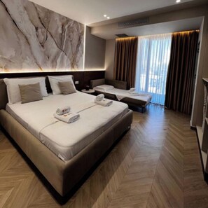 A hotel room with a large bed, a smaller bed, a sofa, and a massage table. - Hotel Memmaj (Ksamil)