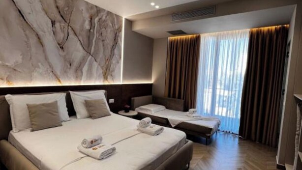 Une chambre d’hôtel avec un grand lit, un lit plus petit, un canapé et une table de massage.
