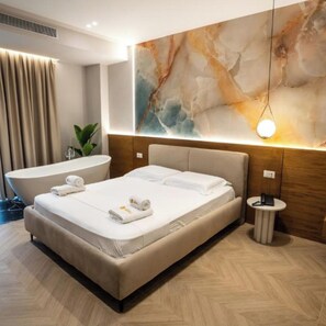 A modern hotel room with a large bed, a bathtub, and a marble wall. - Hotel Memmaj (Ksamil)