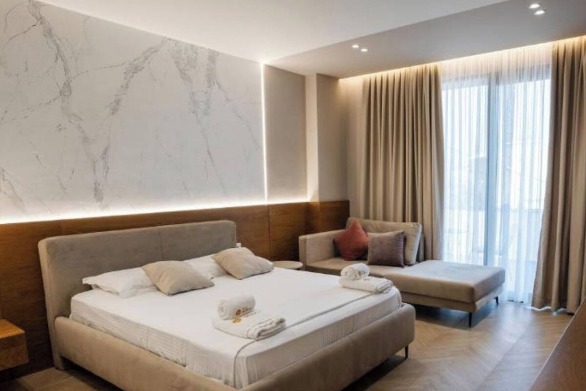 A modern hotel room with a large bed, a sofa, and a desk.