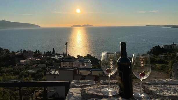 A sunset view from a balcony with a bottle and glasses of wine. - Vila Dena (Vlorë)