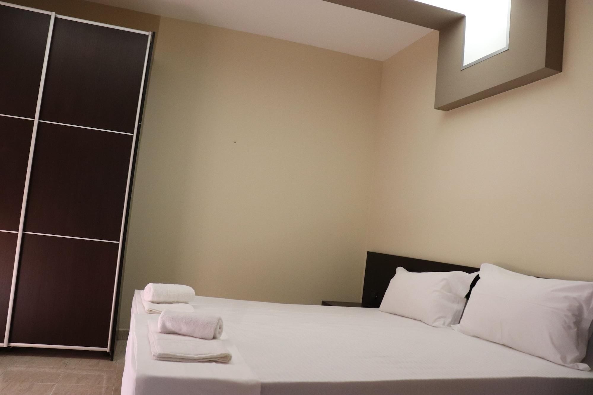A hotel room with a bed, pillows, and a set of towels.