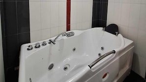 A modern bathroom with a white bathtub, black and white tiled walls, and a red accent strip. - Danis Hotel (Tirana)