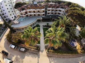 Ein mehrstöckiges Hotel mit Innenhof, Palmen und Schwimmbad.