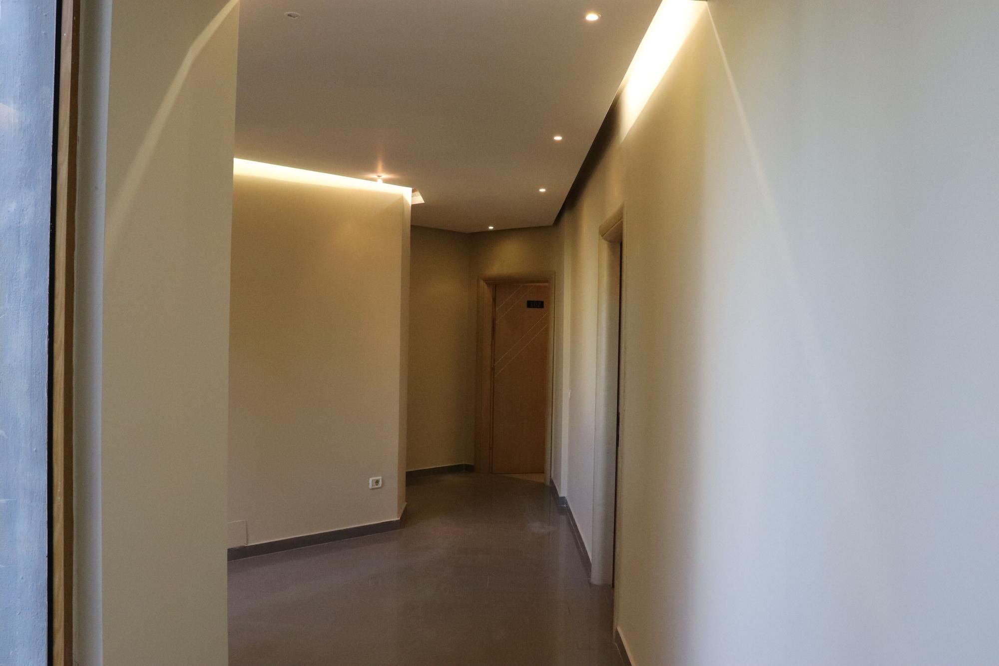Ein Flur mit einer Tür am Ende, eingelassener Beleuchtung und einer schlichten Wand.