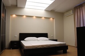 A bedroom with a bed, bedside tables, a ceiling light fixture, and an air conditioning unit. - Danis Hotel (Tirana)