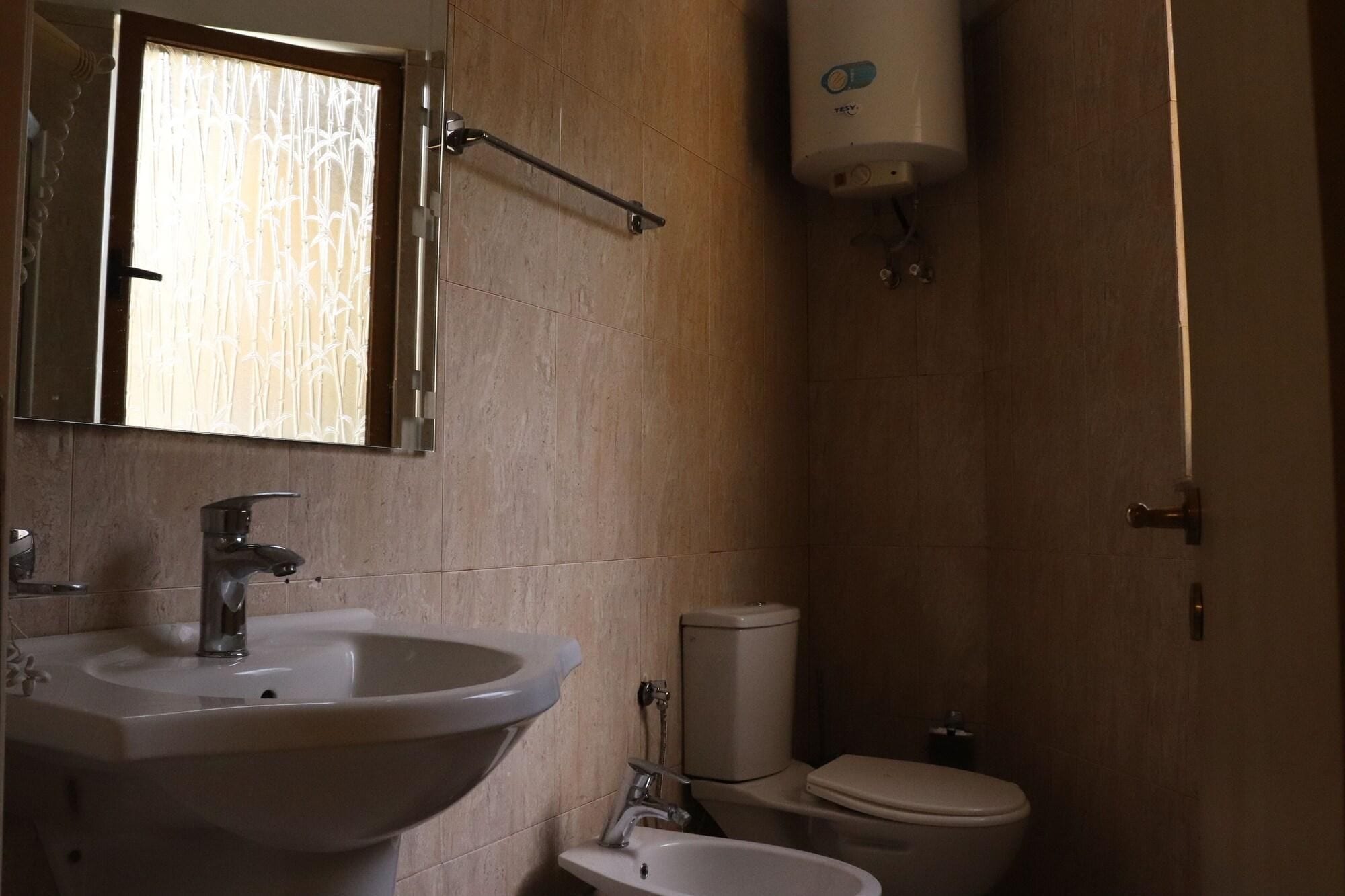 Un baño con lavamanos, inodoro y secamanos.