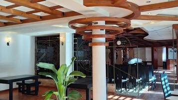 A spacious indoor area with wooden beams, a central column, and a seating arrangement.