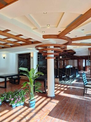 A spacious indoor area with wooden beams, a central column, and a seating arrangement. - Danis Hotel (Tirana)