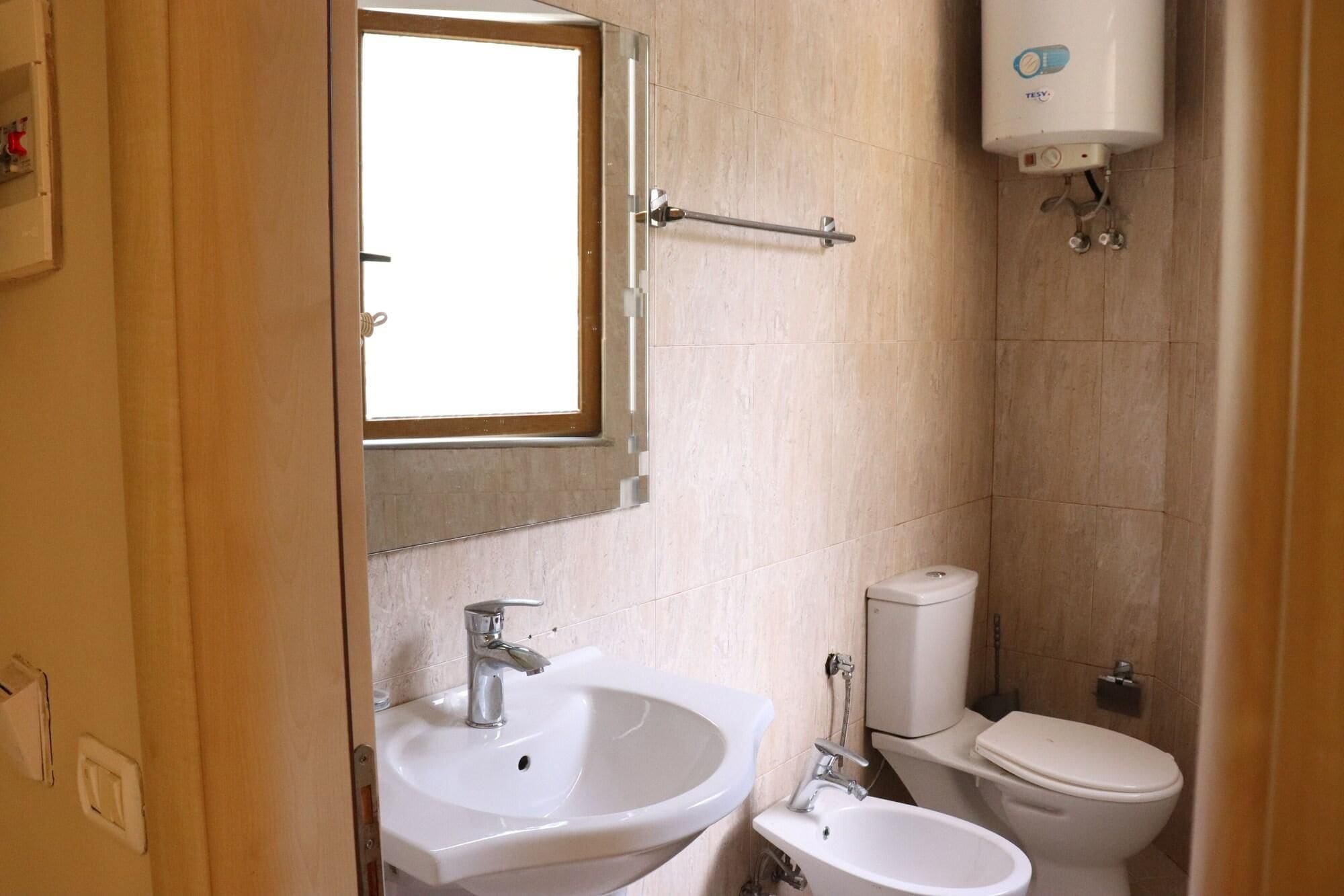 A bathroom with a sink, toilet, and a window.