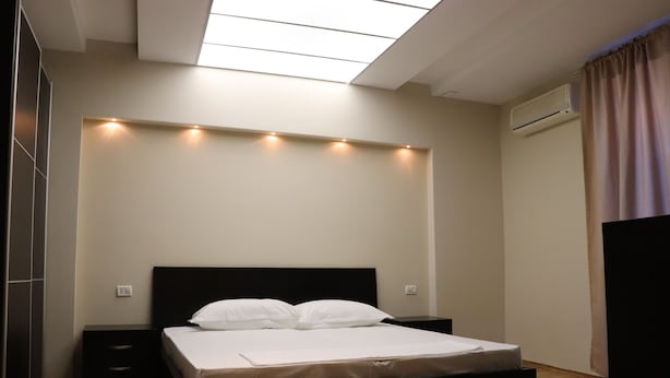 A bedroom with a bed, bedside tables, a wardrobe, and a skylight. - Danis Hotel (Tirana)
