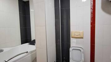 A bathroom with a bathtub, toilet, and a hand dryer.