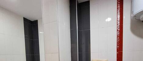 A bathroom with a bathtub, toilet, and a hand dryer.