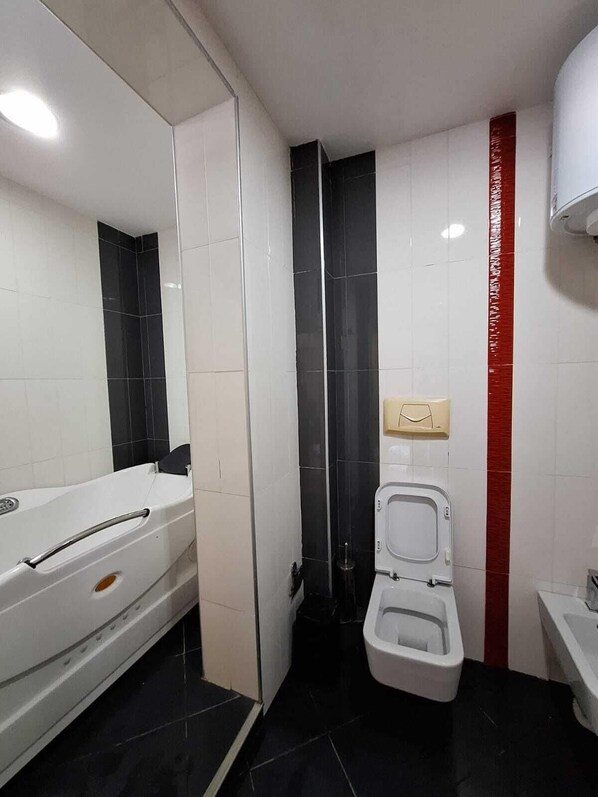 A bathroom with a bathtub, toilet, and a hand dryer. - Danis Hotel (Tirana)