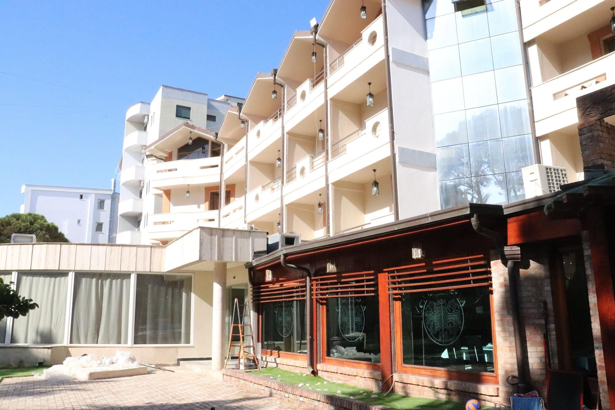 Un edificio de varios pisos con balcones, una zona de estar techada al aire libre y un patio empedrado.