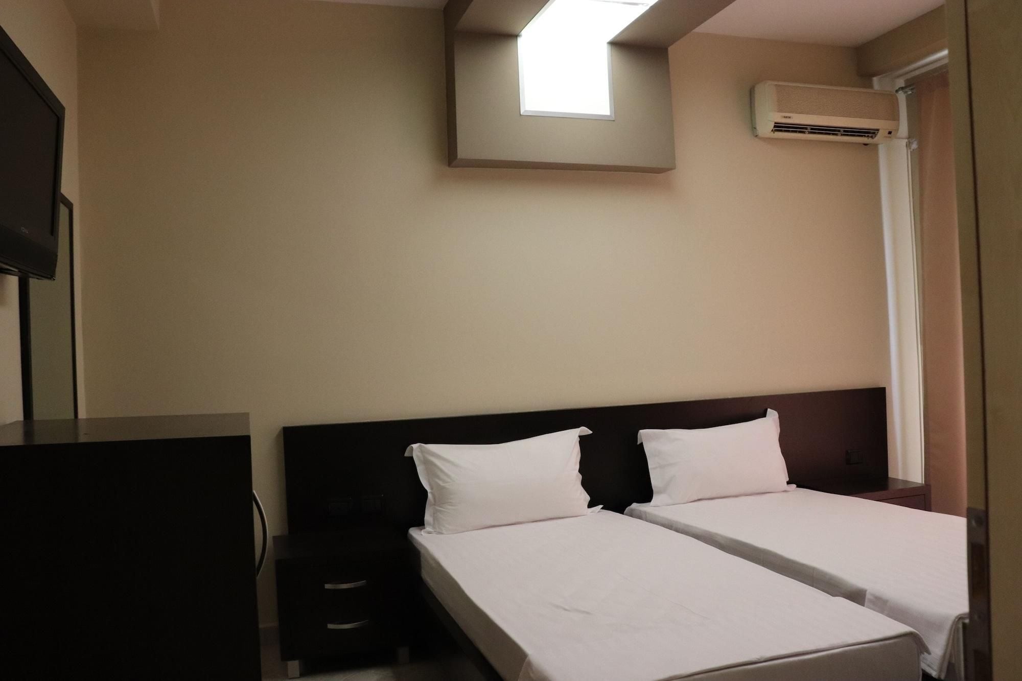 Hotelkamer met twee eenpersoonsbedden, een nachtkastje, een tafeltje, een televisie, een airconditioning en een raam met uitzicht.