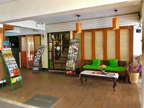 Un área de recepción con piso de madera, un sofá verde con una mesa blanca adelante y un tablón de anuncios con varios objetos.