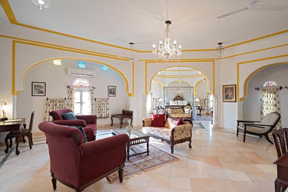 A spacious lobby with classic furniture, a chandelier, and arched doorways.
