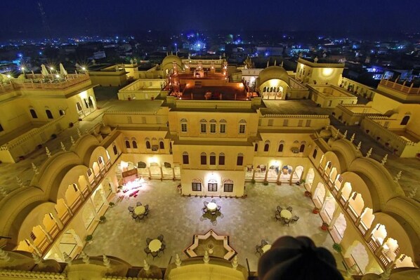 Un amplio y bien iluminado patio con varias zonas de estar y una fuente central, rodeado de arquitectura tradicional.