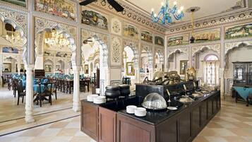 A banquet hall with ornate ceiling murals, chandeliers, and a buffet setup.