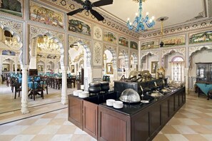 A banquet hall with ornate ceiling murals, chandeliers, and a buffet setup. - Alsisar Mahal- Heritage Palace Hotel (Malasisar)
