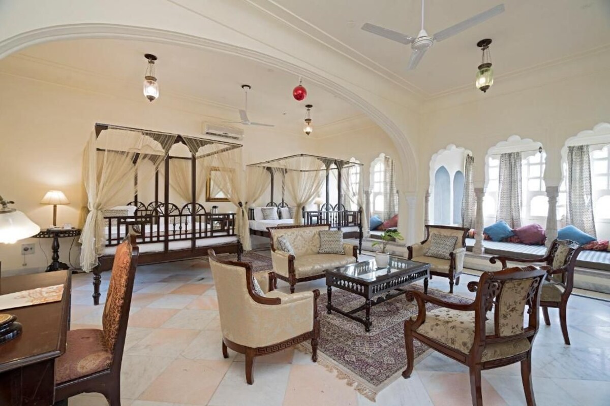 A spacious room with a high ceiling, ornate furniture, and large windows with curtains.