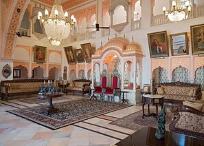 A grand lobby with ornate chandeliers, traditional sofas, and a large patterned rug. - Alsisar Mahal- Heritage Palace Hotel (Malasisar)