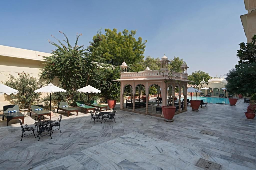 An outdoor patio with marble flooring, lounge chairs, umbrellas, and a gazebo.