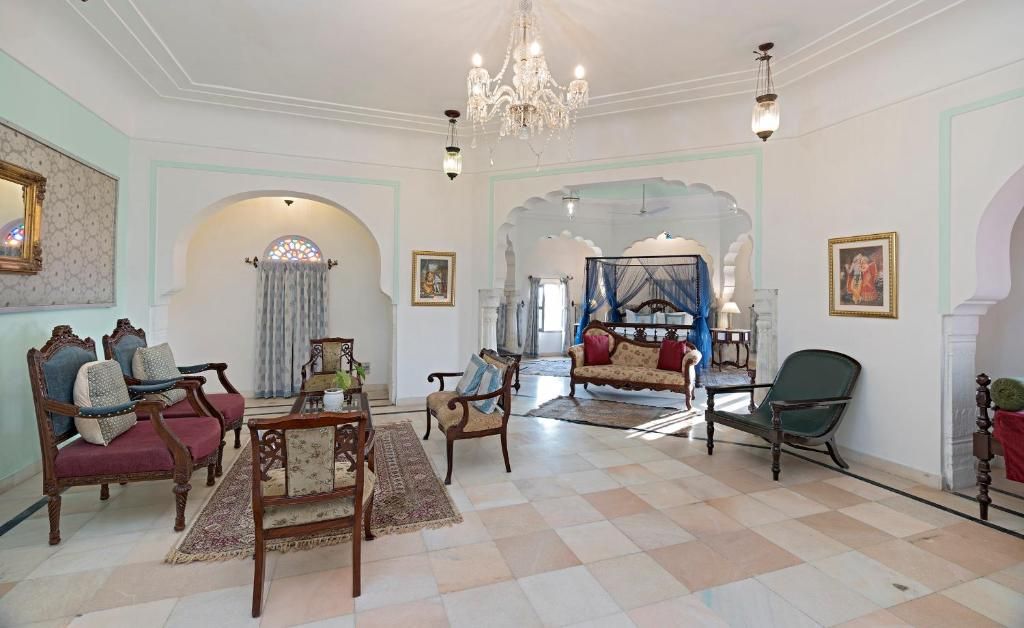 Un salón amplio con muebles ornamentados, una araña y vistas a otra habitación con una cama.