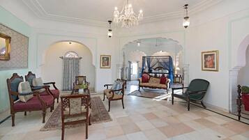 Un salón amplio con muebles ornamentados, una araña y vistas a otra habitación con una cama.