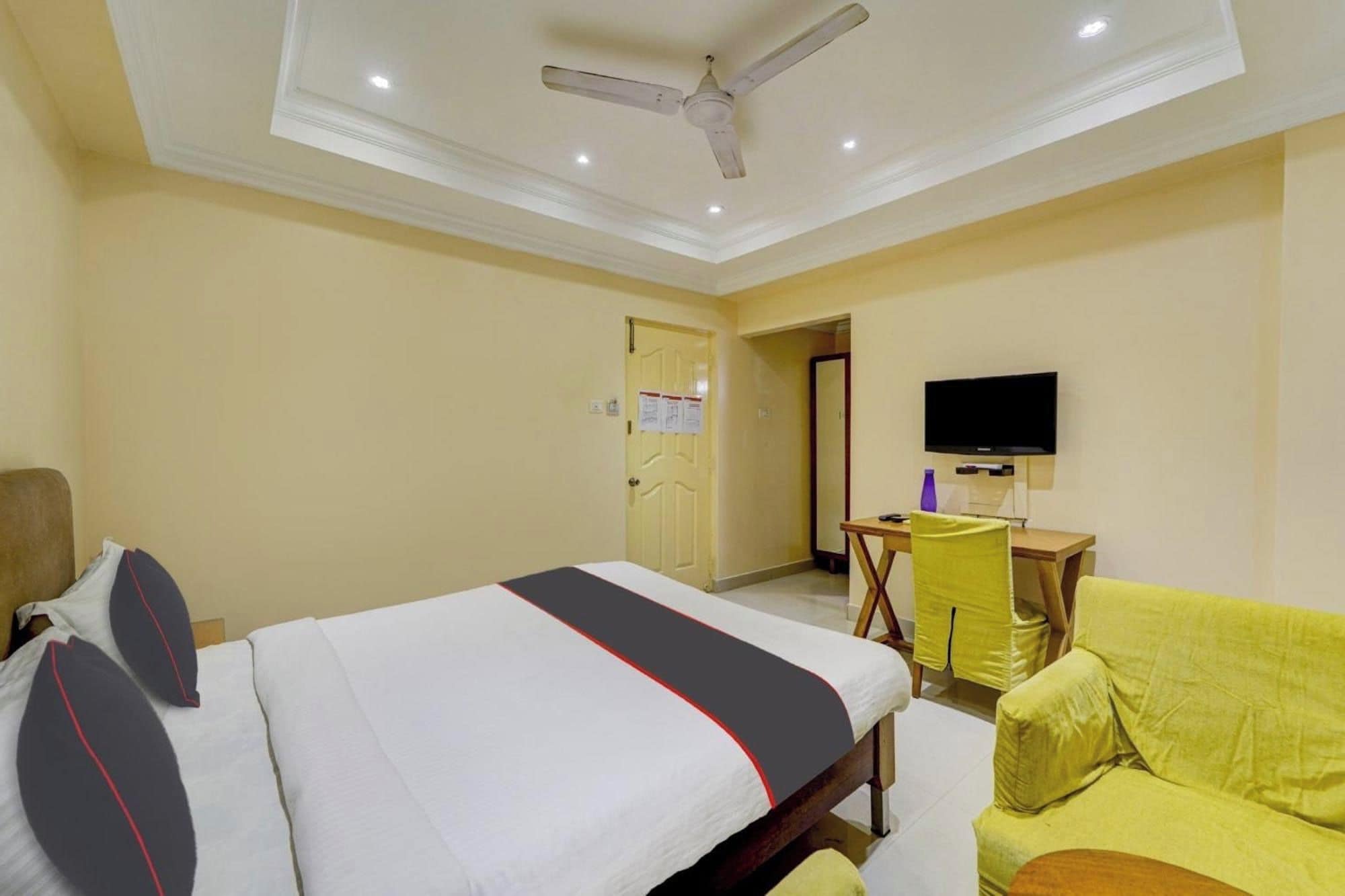 A hotel room with a bed, a desk, a chair, and a television.