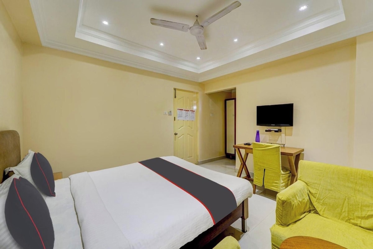A hotel room with a bed, a desk, a chair, and a television.