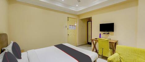 Una habitación de hotel con una cama, un escritorio, una silla y un televisor.
